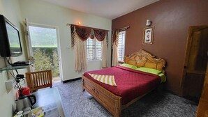 A bedroom with a wooden bed, a desk with a chair, a television, and a window with curtains.