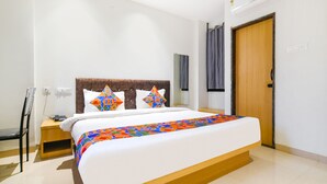 A modern hotel room with a large bed, wooden headboard, and a colorful bedspread. - Fabhotel Aashiyana (Indore)