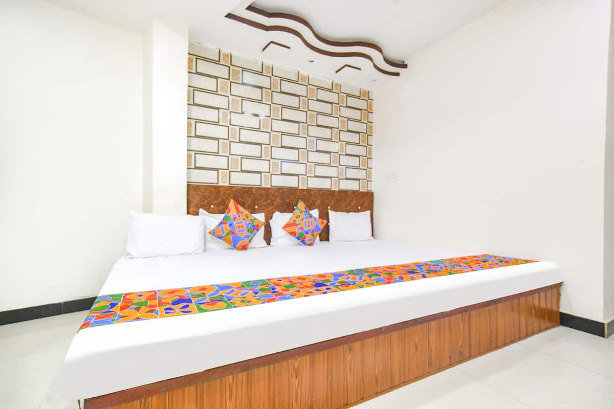 Un dormitorio moderno con cabecera de madera, colcha estampada y un panel decorativo en la pared.