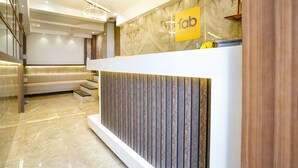 A modern hotel reception area with a marble reception desk, a staircase, and a sign for 'fab hotels'. - FabHotel Shubham Inn (Mumbai)
