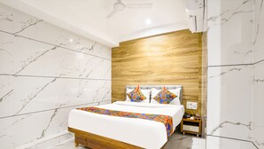 A modern bedroom with a wooden bed frame, a marble-patterned wall, and a wooden headboard. - FabHotel Shubham Inn (Mumbai)