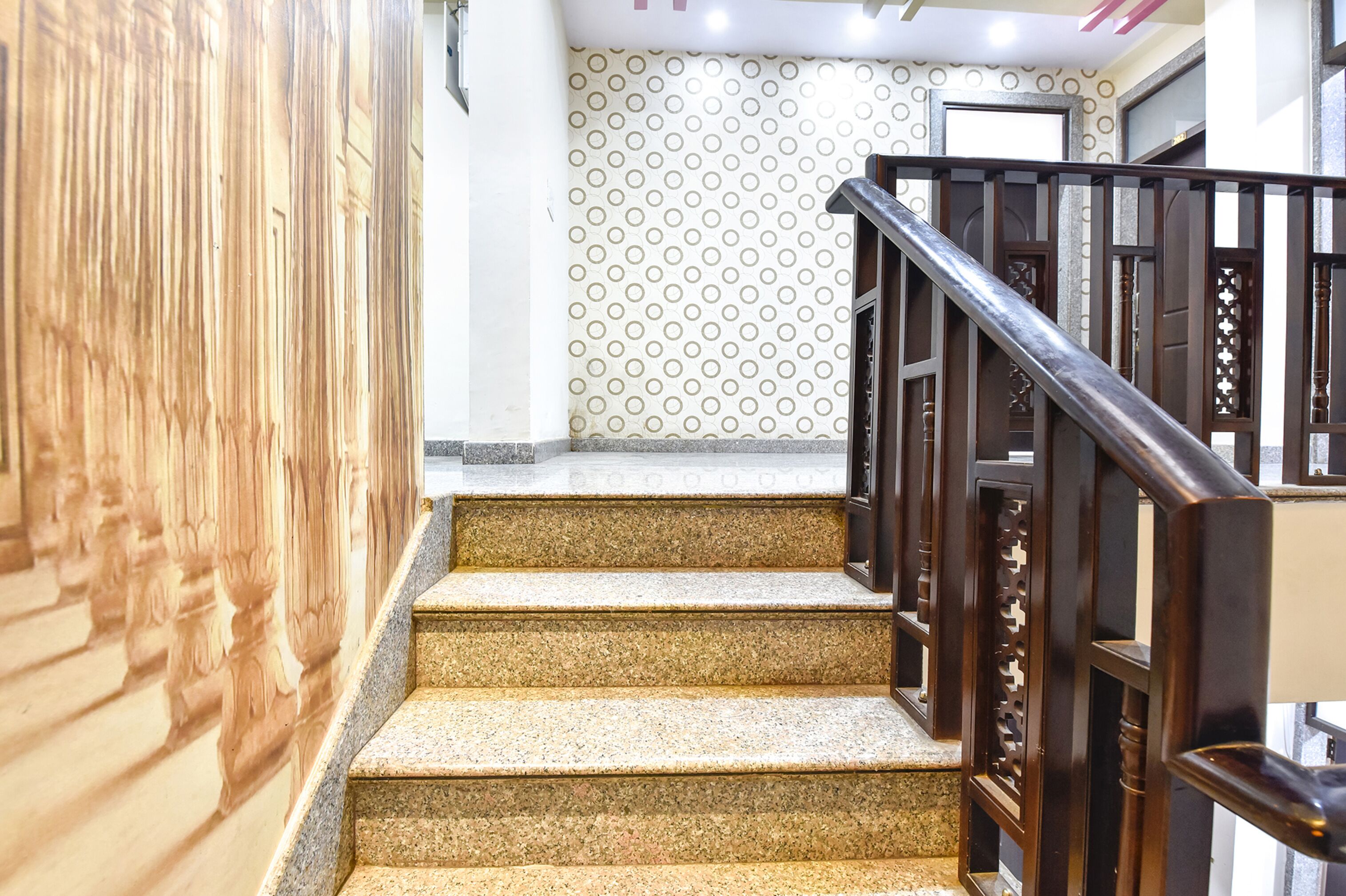 A staircase with wooden railings and a patterned wall in the background.