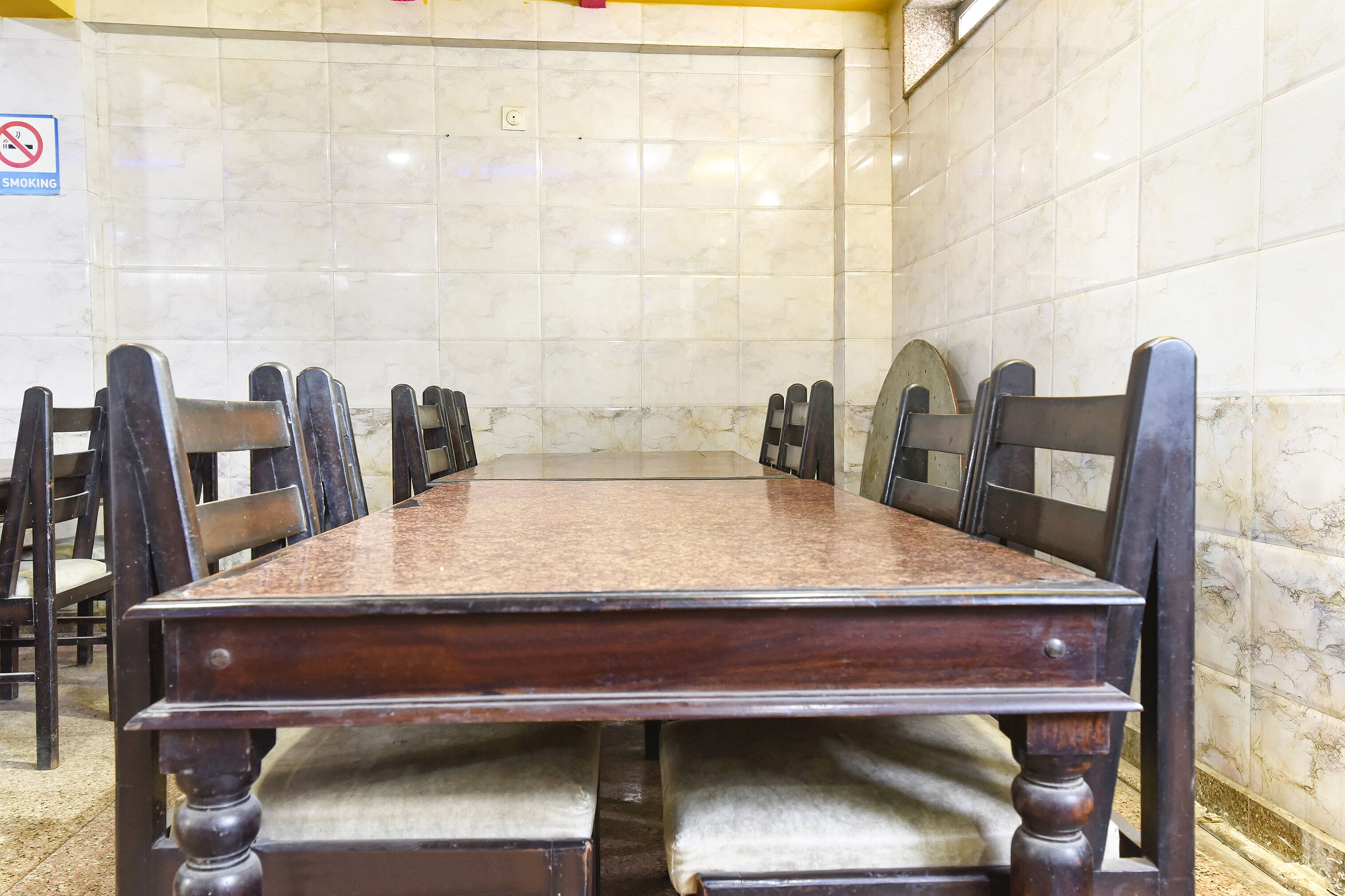Une salle de conférence avec un mur recouvert de carreaux de marbre, une table en bois et des chaises assorties.
