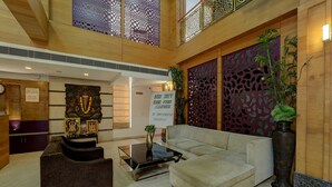 A lobby with a sofa, coffee table, decorative wall, and a sign prohibiting food and drink. - FabHotel JVH (Bengaluru)