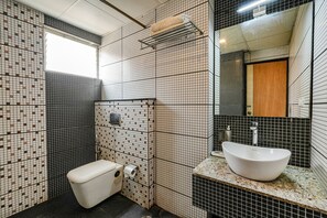 A bathroom with a toilet, sink, and mirror. - FabHotel JVH (Bengaluru)