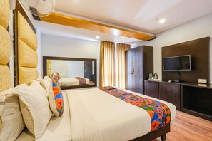 A hotel room with a large bed, a television, a mirror, and a wardrobe. - FabHotel JVH (Bengaluru)