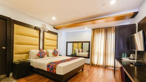 A hotel room with a bed, bedside table, mirror, curtains, and a TV. - FabHotel JVH (Bengaluru)