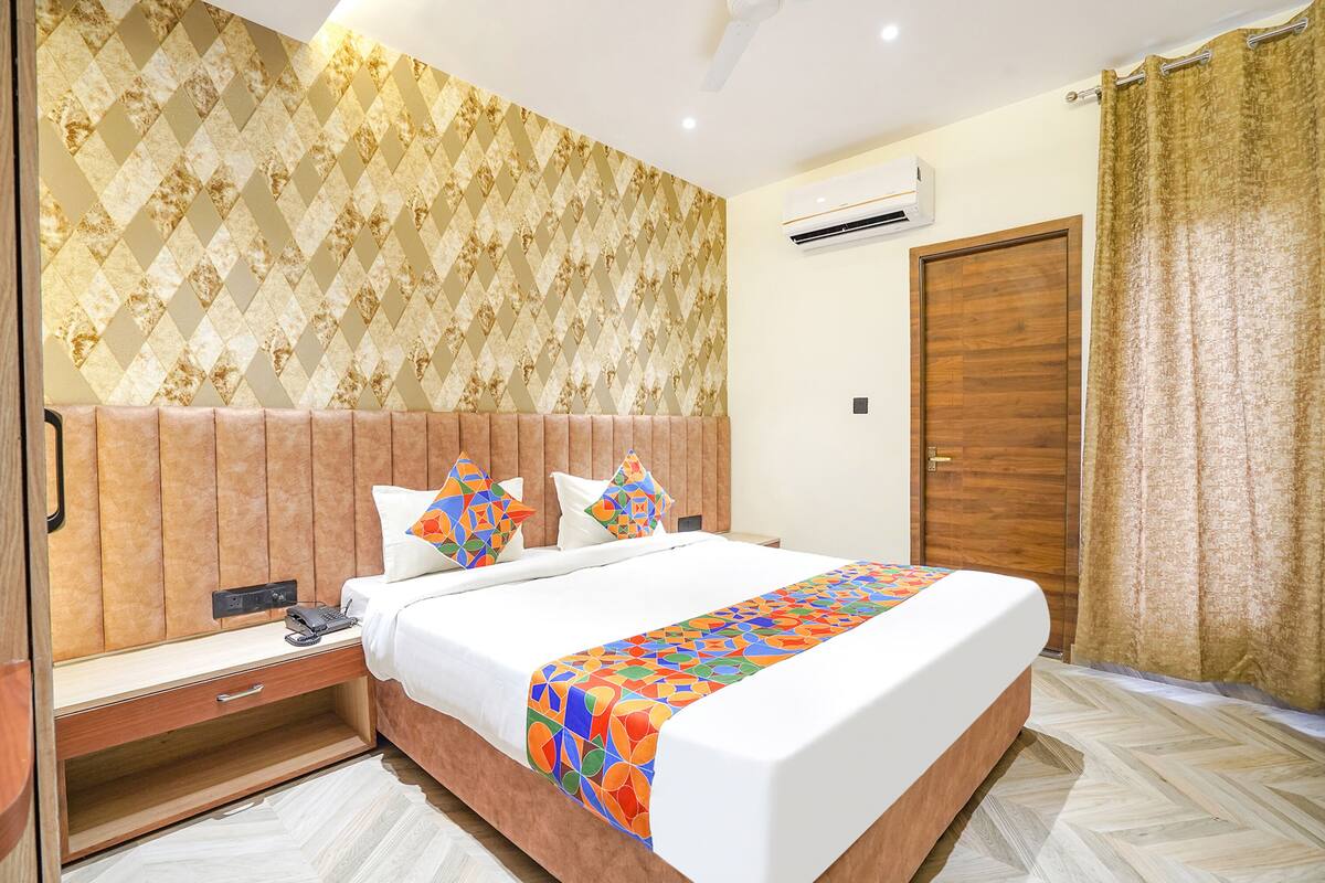 A hotel room with a large bed, wooden headboard, and a patterned wallpaper.