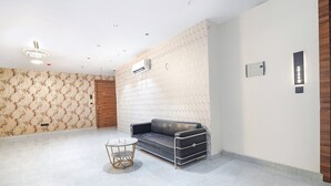 A modern room with a patterned wall, a leather sofa, a small round table, and recessed ceiling lighting. - Fabhotel The Comfort Inn (Kanpur)