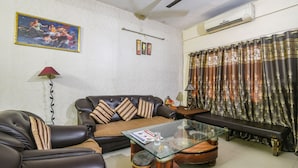 A living room with a sofa, coffee table, and a ceiling fan. - Fabhotel Maadhavam Residence (Patna)
