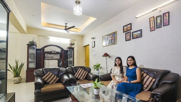 A living room with two sofas, a glass coffee table, and a ceiling fan. - Fabhotel Maadhavam Residence (Patna)