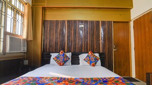 A hotel room with a large bed, wooden headboard, and a colorful bedspread. - Fabhotel Maadhavam Residence (Patna)
