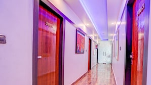 A hotel hallway with wooden floors, doors labeled with room numbers, and a marble wall at the end. - Fabhotel Prime Stay Inn I (Varanasi)