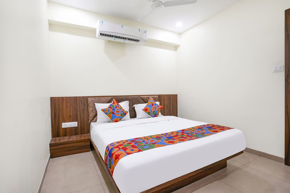 A neatly made bed with a colorful blanket, a wooden headboard, and a white wall.