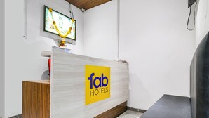 Una recepción con un letrero de 'Fab Hotels', un televisor y un mostrador de madera.