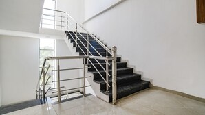 Una escalera moderna con barandilla de metal y peldaños negros, que conduce a un piso superior.