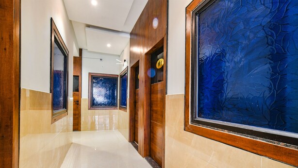 Un pasillo con puertas de madera y un amplio panel de vidrio decorativo azul a la derecha.