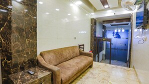 A lobby with a sofa, a marble floor, and a ceiling fan. - Fabhotel East Patel Nagar (New Delhi)