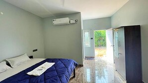 A bedroom with a bed, a wardrobe, and a door leading to a balcony. - Fabexpress Selvas Eden Resort (Puducherry)