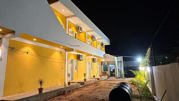 A modern two-story building with a yellow facade and white accents, featuring a covered outdoor area with potted plants. - Fabexpress Selvas Eden Resort (Puducherry)