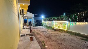 A courtyard with a paved walkway, potted plants, and a building with a yellow facade. - Fabexpress Selvas Eden Resort (Puducherry)