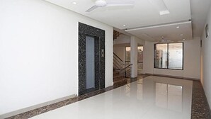 A spacious hallway with a polished floor, a ceiling fan, and a door leading to a staircase. - Fabhotel Taj Castle (Agra)