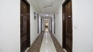 A long, narrow hallway with dark wooden doors on both sides, leading to a room at the end. - Fabhotel Taj Castle (Agra)