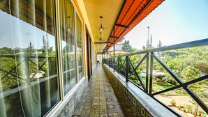 A corridor with patterned floor tiles, large windows, and a balcony with potted plants. - Fabhotel Prime 4D'S Coast Resort (Vagator)