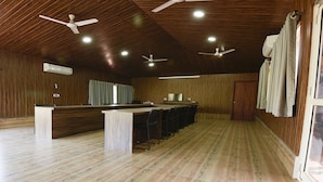 A spacious room with wooden floors, a long counter with chairs, ceiling fans, and recessed lighting. - Fabhotel Prime 4D'S Coast Resort (Vagator)