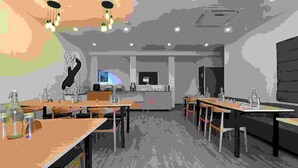 Un comedor moderno con varias mesas y sillas, una barra con exhibición y un reloj grande en la pared.