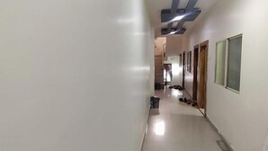A hallway with a ceiling light, a trash bin, and a shoe rack. - Fabexpress Rudraksh Palace (Ujjain)