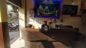 A reception desk with a blue neon sign, a wall clock, and a framed picture. - Fabexpress Rudraksh Palace (Ujjain)