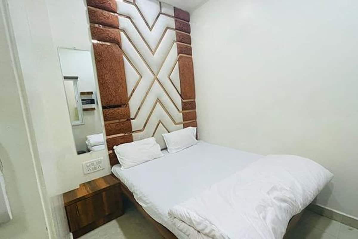 A bedroom with a bed, a wooden headboard, a nightstand, and a mirror.