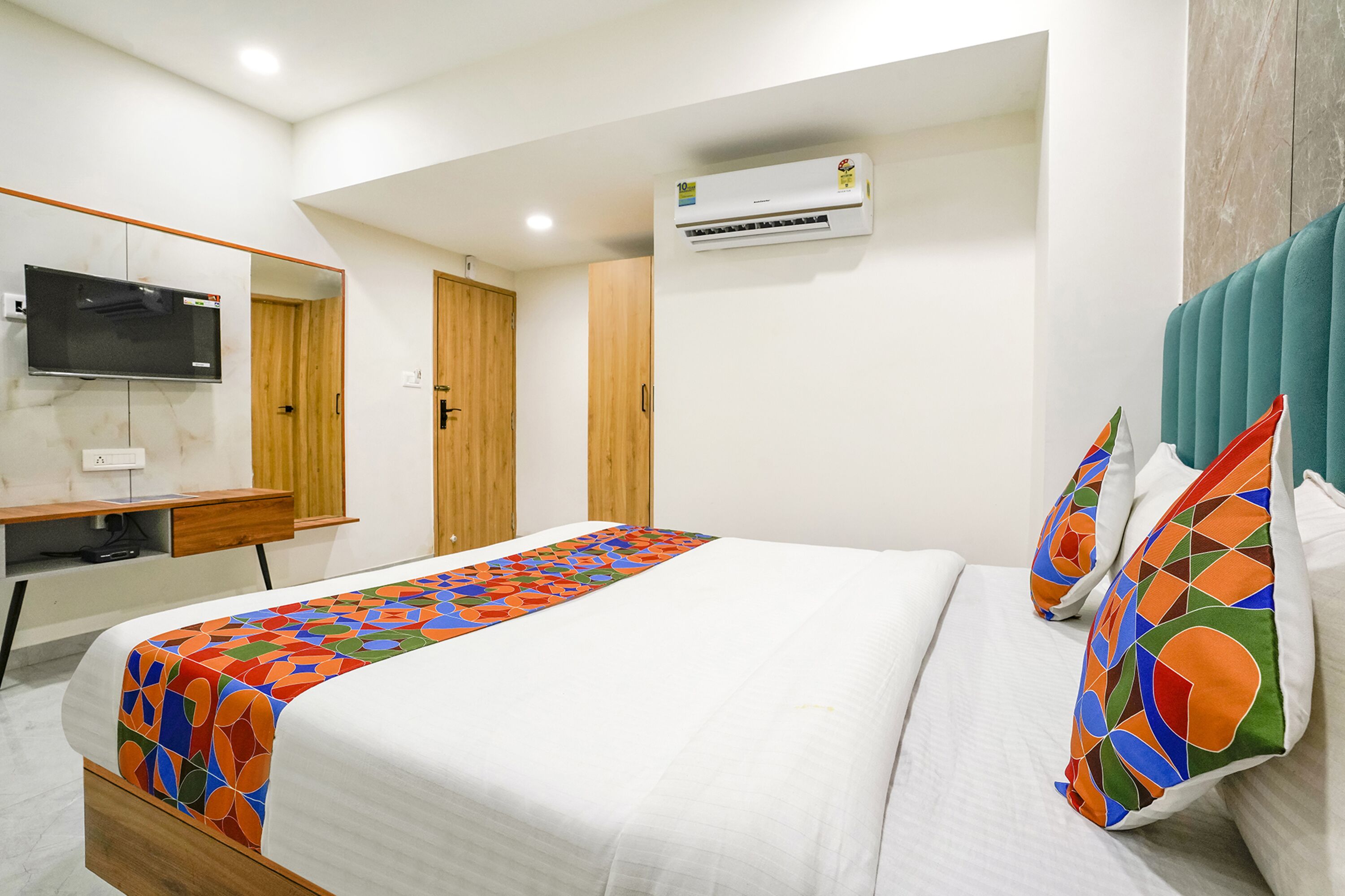 Une chambre d’hôtel équipée d’un lit, d’une télévision, d’un climatiseur et d’une armoire en bois.