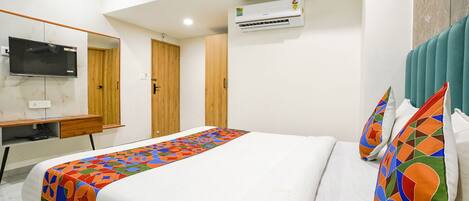 Une chambre d’hôtel équipée d’un lit, d’une télévision, d’un climatiseur et d’une armoire en bois.