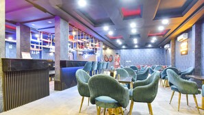 A restaurant with a bar area, multiple seating arrangements, and a modern interior design. - Fabhotel Golden Palms (Udaipur)
