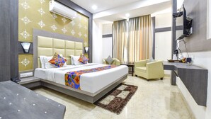 A modern hotel room with a large bed, a desk, a chair, and a TV mounted on the wall. - Fabhotel Golden Palms (Udaipur)