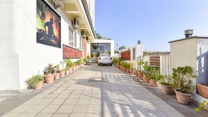 A paved pathway lined with potted plants leading to a building entrance. - Fabhotel Golden Palms (Udaipur)