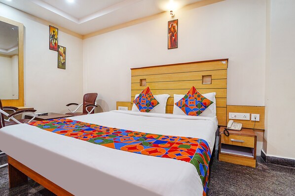 A hotel room with a large bed, a wooden headboard, a bedside table with a phone, and a chair. - Fabhotel Slv Grand (Tirupati)