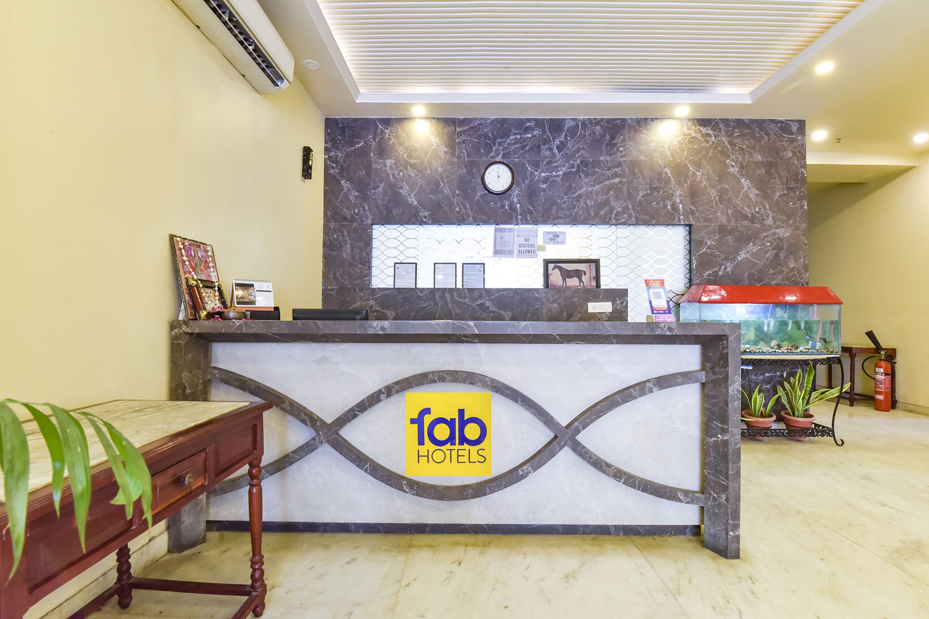 A hotel reception desk with a marble wall, a clock, and a sign reading "fab hotels".