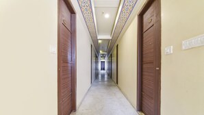 Un long couloir étroit, avec des portes en bois de chaque côté et un plafond orné de motifs.