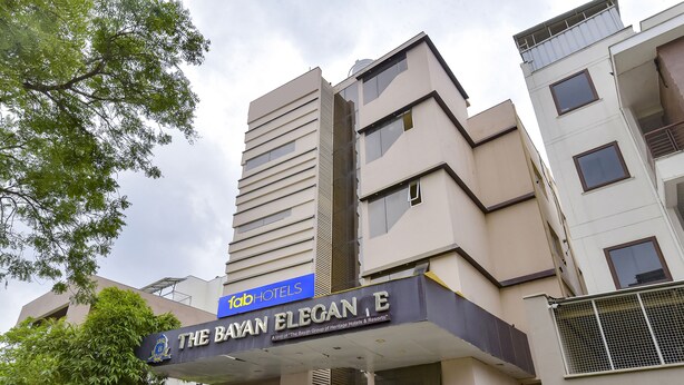 Un hôtel appelé « The Bayan Elegance », doté d’une architecture moderne, se distingue par son entrée imposante et son enseigne bien visible.