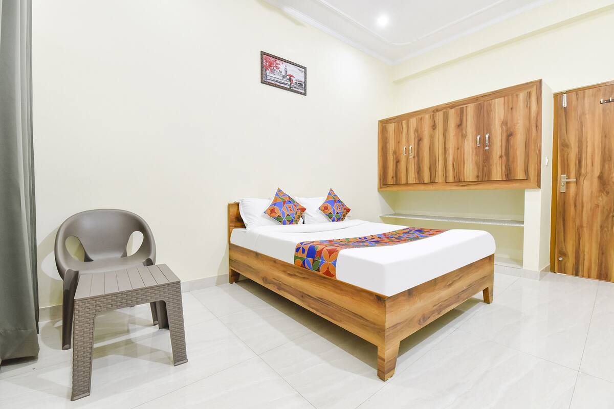 A bedroom with a wooden bed, a grey plastic chair, and a wooden wardrobe.