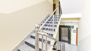 A staircase with metal railings and granite steps leading to a door with a sign above it. - Fabhotel Living (Jaipur)