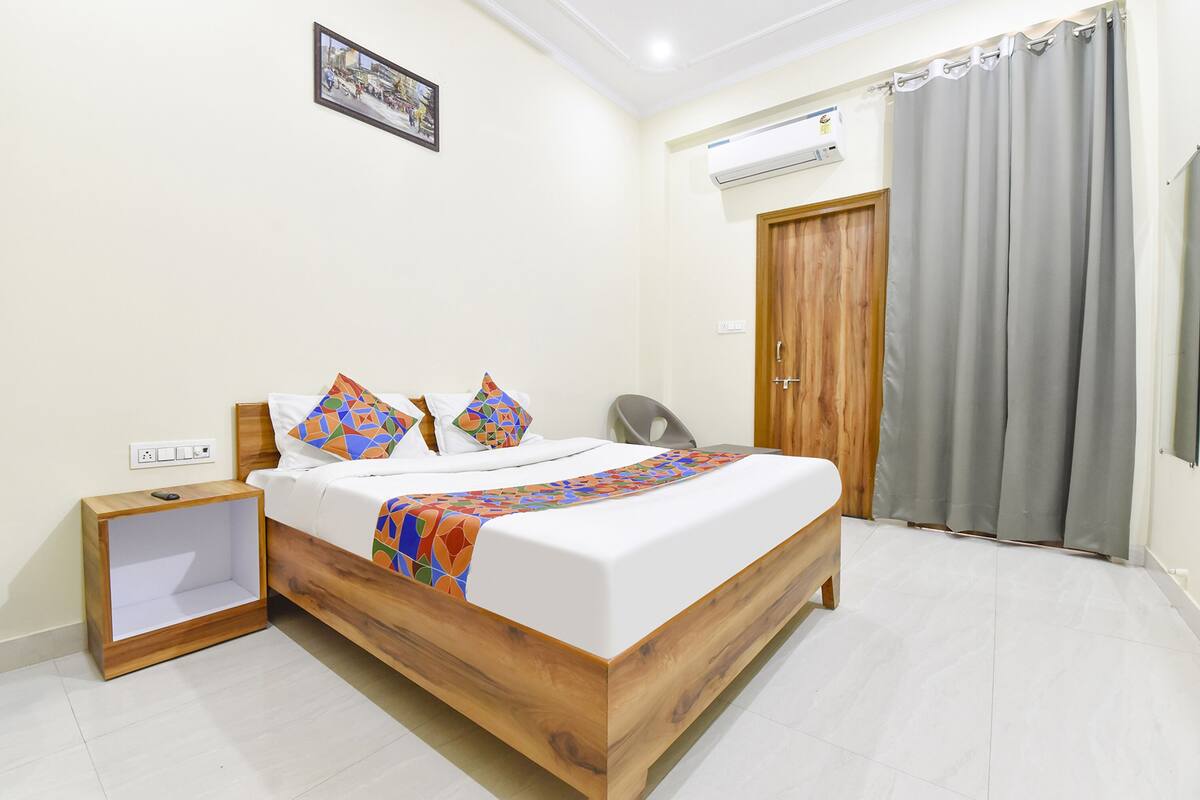 A neatly arranged bedroom with a wooden bed, a bedside table, a chair, and a grey curtain.