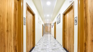 A hallway with wooden doors, patterned floor tiles, and recessed ceiling lights. - Fabhotel Living (Jaipur)