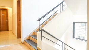 A modern interior with a staircase, a wooden door, and a window with a view. - Fabhotel Saffron Inn I (Pune)