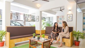 A modern waiting area with wooden benches, a coffee table, and potted plants. - Fabhotel Saffron Inn I (Pune)
