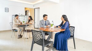 A meeting room with a round table, four chairs, and a whiteboard. - Fabhotel Saffron Inn I (Pune)