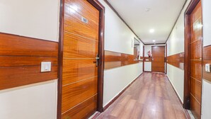 A hallway with wooden doors and a tiled floor. - Fabhotel Dwarka Suites (New Delhi)